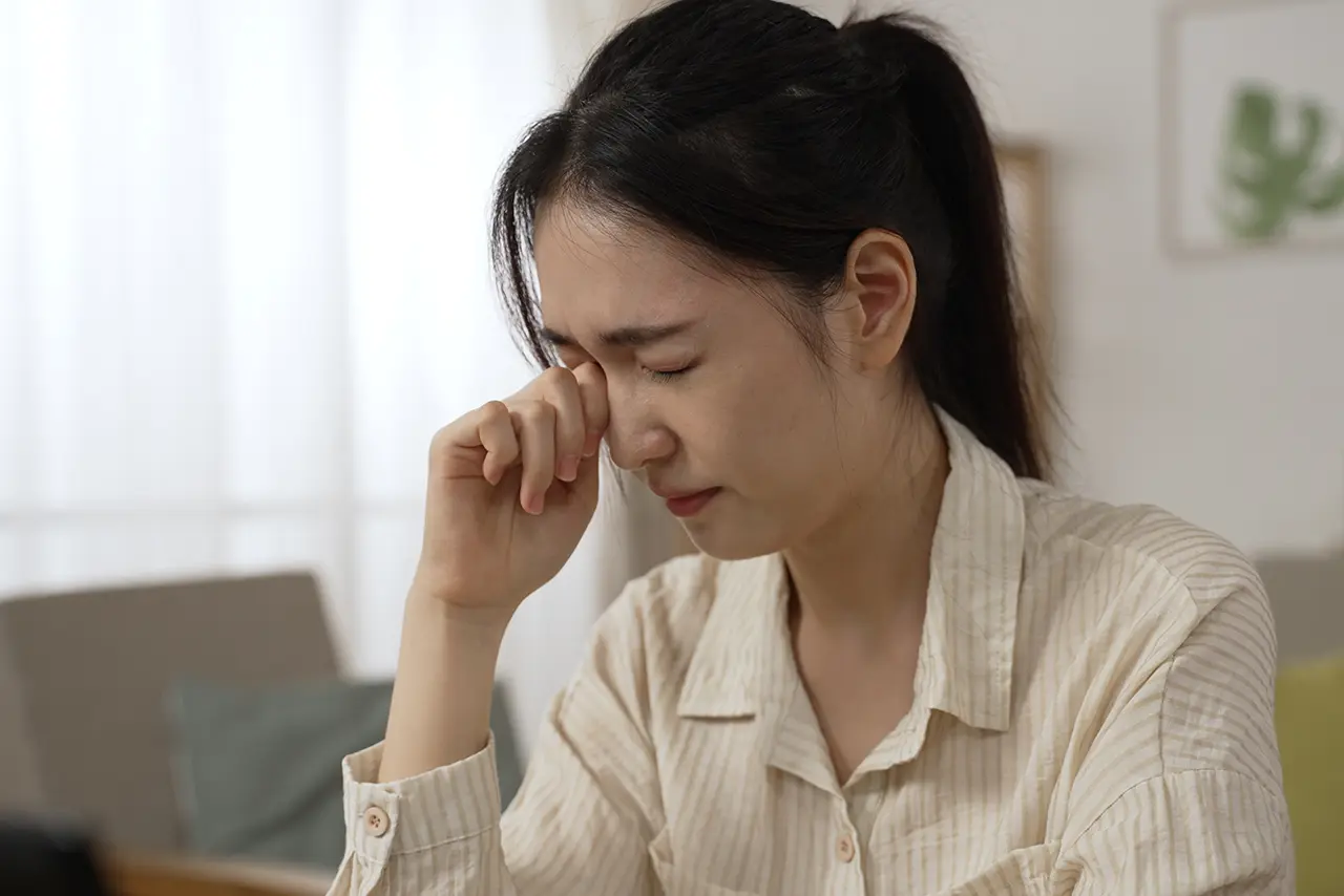 A woman feeling eye fatigue, highlighting the need for low-maintenance vision solutions like ICL