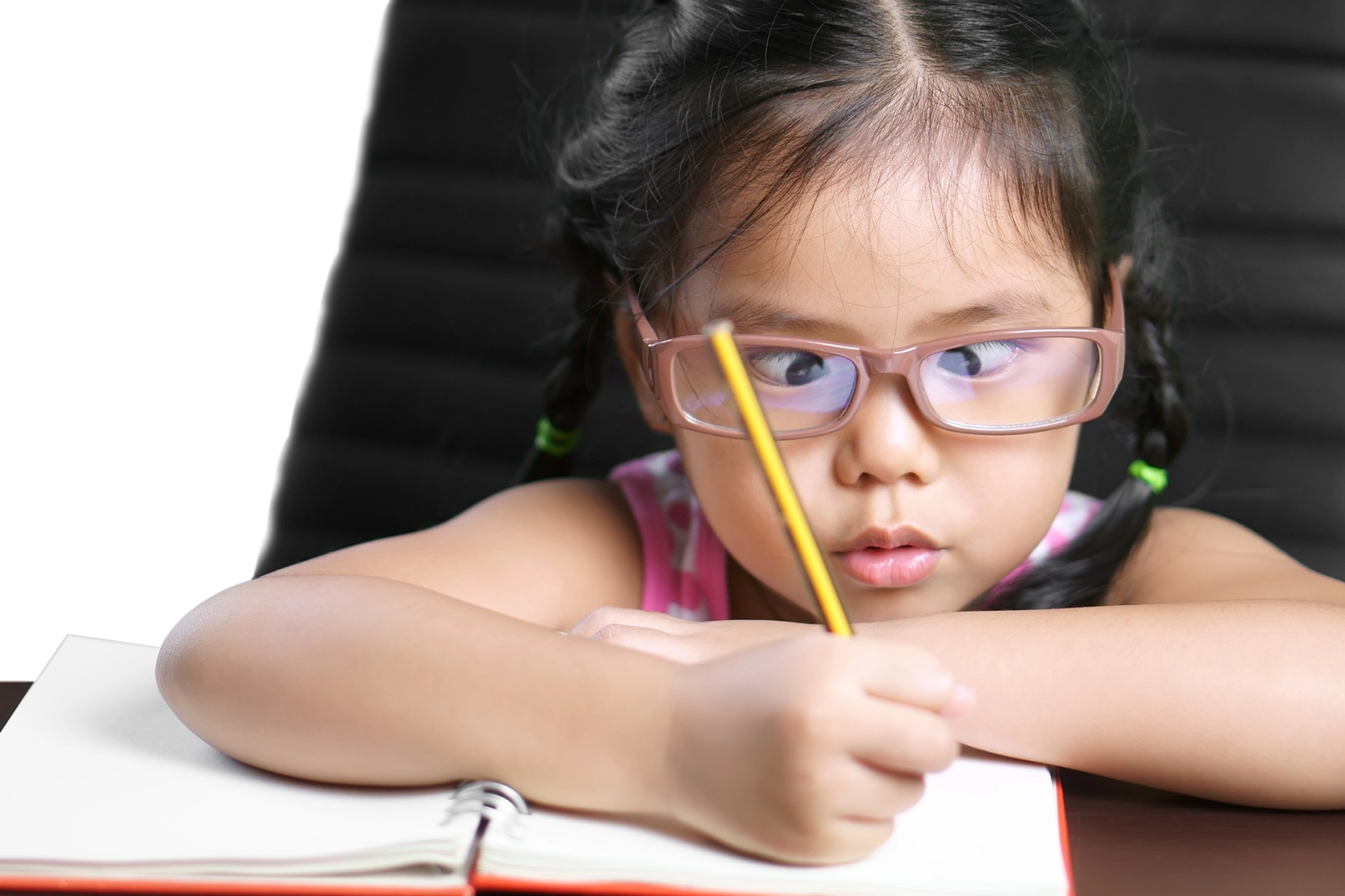 Young girl with strabismus attempting school work.