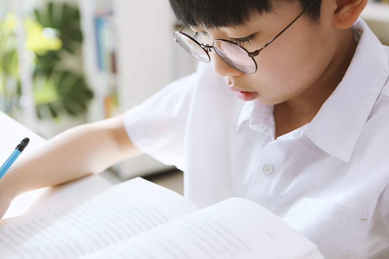 Young boy wearing glasses while studying.
