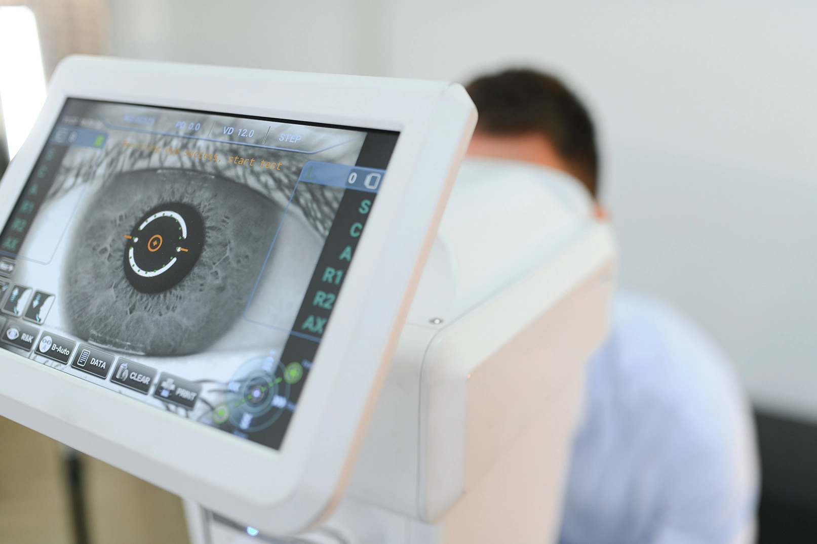 Young man having an eye examination, monitor with a close up view of his eye