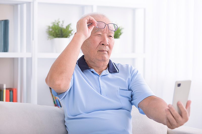 Man having difficulty seeing clearly while using his phone.